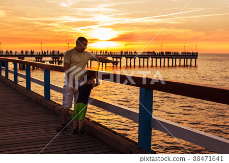 pier on the sea. sunset. Palanga. father and son walking along the waterfront pier on the sea. sunset. Palanga. father and son walking along the waterfront 88471641