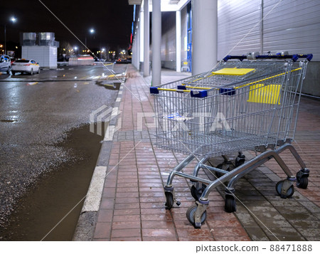 An empty shopping cart with the blue and yellow color next to the store. 88471888