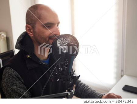 adult podcaster badult podcaster blogger smiling while broadcasting his live audio podcast in the studio using logger smiling while broadcasting his live audio podcast in the studio using a microphone adult podcaster badult podcaster blogger smiling while broadcasting his live audio podcast in the studio using logger smiling while broadcasting his live audio podcast in the studio using a microphone 88472342