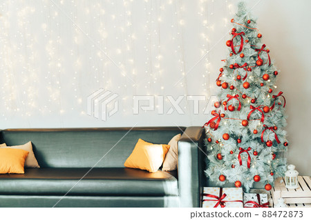 White decorated christmas tree with gift boxes standing next to the sofa 88472873