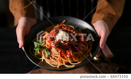 Top view, Female hands holding or serving a plate of Italian spaghetti 88473350