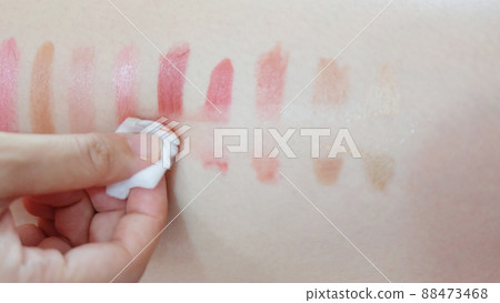 Hand wiping off lipstick patches drawn on a skin, with a piece cotton pad. Hand wiping off lipstick patches drawn on a skin, with a piece cotton pad. 88473468