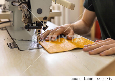 Close up craftsman hands sew stuff blank for wallet use sewing machine. Working at leather workshop 88474619