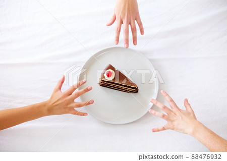 Mine. Three hands reaching for the last piece of cake. Mine. Three hands reaching for the last piece of cake. 88476932