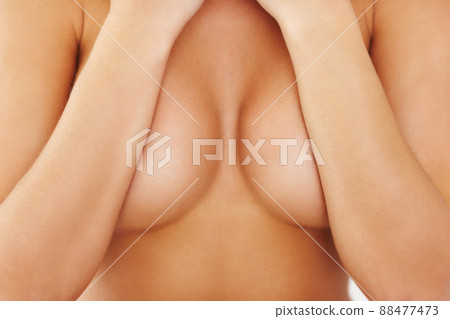 Embracing femininity. Shot of a woman covering her bare breasts. 88477473