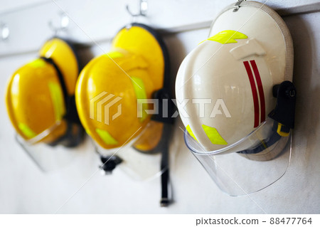 Protected against work hazards. Shot of firemens helmets hanging from a wall. 88477764