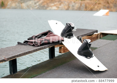 A wakeboard and kit. Cropped view of a wakeboard alongside the lake. 88477999
