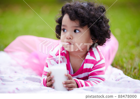 Mmmmm. Adorable little girl drinking milk through a straw while lying on the grass. 88478000
