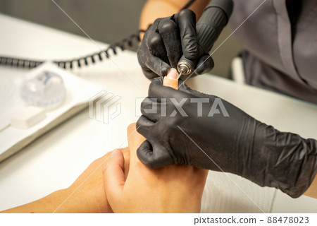Manicure master uses electric nail file machine in a nail salon, close up Manicure master uses electric nail file machine in a nail salon, close up 88478023