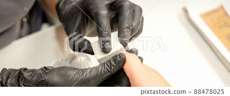 Close up of the caucasian hands of a professional manicurist are filing the nails of a young woman. Young caucasian woman receiving a manicure by a beautician with a nail file in a nail salon Close up of the caucasian hands of a professional manicurist are filing the nails of a young woman. Young caucasian woman receiving a manicure by a beautician with a nail file in a nail salon 88478025