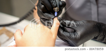 Manicure master uses electric nail file machine in a nail salon, close up Manicure master uses electric nail file machine in a nail salon, close up 88478059