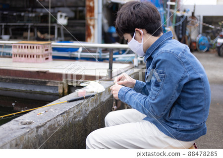 A boy enjoying fishing in a fishing pond 88478285