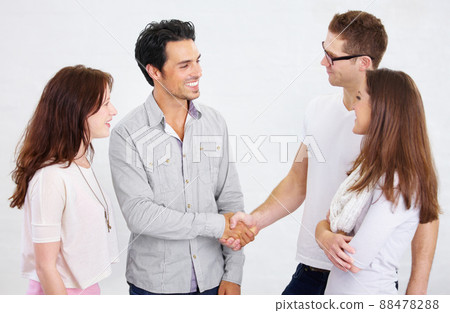 We owe our teams success to you. Shot of a two young business professionals shaking hands while their coworkers look on. We owe our teams success to you. Shot of a two young business professionals shaking hands while their coworkers look on. 88478288