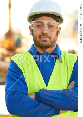 Professional - Hell get the job done. A stern construction working wearing protective glasses and crossing his arms. Professional - Hell get the job done. A stern construction working wearing protective glasses and crossing his arms. 88478290