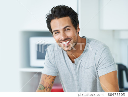 Hes happy in his bachelor flat. Cropped portrait of a handsome young man in his kitchen. 88478505