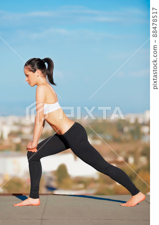 Calm morning workout. Shot of an attractive young woman in workout gear doing yoga on a rooftop. Calm morning workout. Shot of an attractive young woman in workout gear doing yoga on a rooftop. 88478517