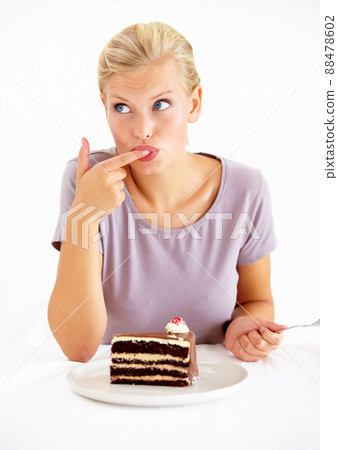 Trying a small taste.... Young woman tasting the frosting of a delicious piece of chocolate cake. 88478602