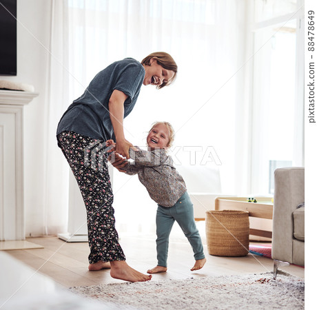 I want to dance with my mom. Full length shot of an attractive young mother and playing with her daughter in the living room at home. 88478649