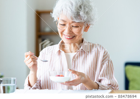 Senior woman eating yogurt Senior woman eating yogurt 88478694