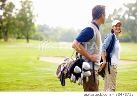 Female golfer smiling and looking at man. Focus on female golfer smiling and looking at man. Female golfer smiling and looking at man. Focus on female golfer smiling and looking at man. 88478732
