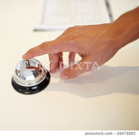 Ringing in his holiday. Shot of a hand ringing a bell at a hotel check in counter. Ringing in his holiday. Shot of a hand ringing a bell at a hotel check in counter. 88478805