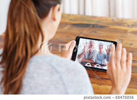 Chatting to her folks. A young woman using a digital tablet for a video call with her family. Chatting to her folks. A young woman using a digital tablet for a video call with her family. 88478856