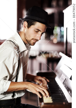 Expressing the music from deep within his soul. A handsome young man playing the piano in a club. 88479052