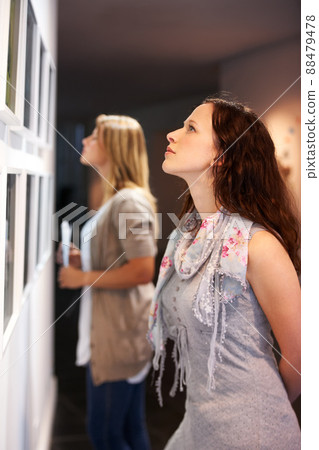 Taking in a century of art. Shot of a young woman looking at paintings in a gallery. 88479478