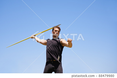 this is going the distance. Shot of a lone man throwing a javelin outside. 88479980