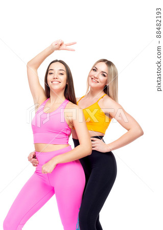 Two beautiful, athletic, slim and cheerful female friends are smiling. Lifestyle concept with sports and gym. Isolated on white background. Two beautiful, athletic, slim and cheerful female friends are smiling. Lifestyle concept with sports and gym. Isolated on white background. 88482193