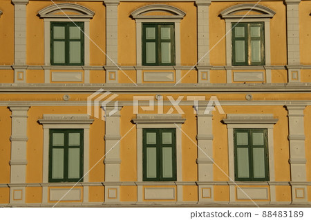 Yellow retro Europe style building and green rectangle shape windows. 88483189