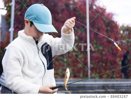 Children enjoying fishing in the fishing pond Children enjoying fishing in the fishing pond 88483287