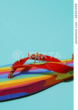 closeup of miniature men on a rainbow flip-flop 88483499