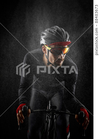 male cyclist riding road bicycle on black background 88483673