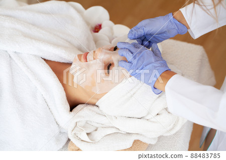 Beautiful young woman use sheet facial mask on face skin for beauty spa 88483785