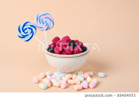 Sweet gummy in cup and marshmallow on pastel orange background. 88484055