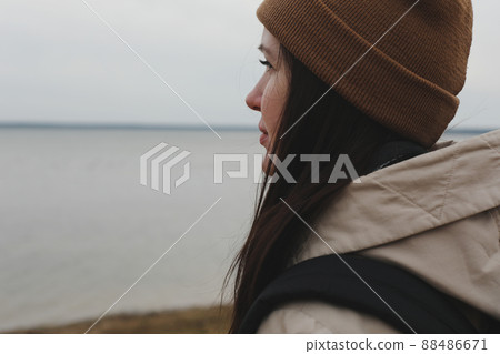 Portrait of young woman in a hat looking over the sea or the ocean, enjoying amazing nature, feeling of freedom 88486671