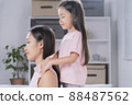 The daughter is giving a massage to her mother. 88487562