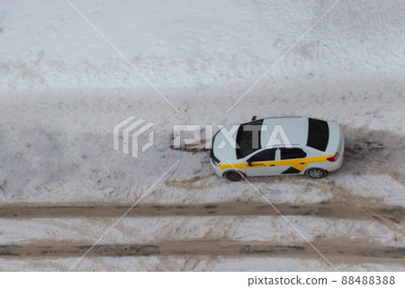 taxi car in the parking lot near the road top view in winter, footprints in the snow 88488388