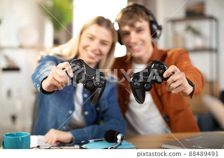 Handsome man and pretty blond woman, showing wireless joysticks to camera 88489491