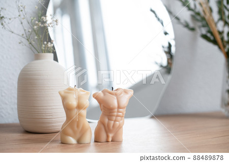 Candles in the form of naked female and male bodies on a table in a bright room at home. Pleasant visual content in natural earthy tones Candles in the form of naked female and male bodies on a table in a bright room at home. Pleasant visual content in natural earthy tones 88489878