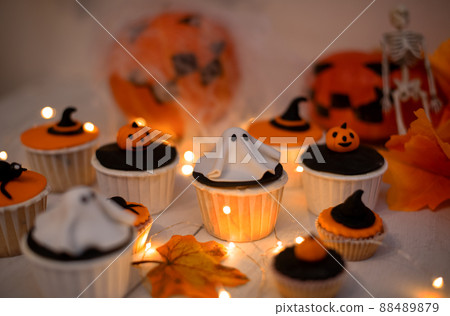 Halloween muffins with decorations in the form of ghosts, pumpkins and witch hats. A set of festive cupcakes and treats for a Halloween party 88489879
