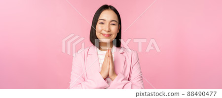 Thank you. Smiling asian saleswoman, corporate lady in suit thanking, holding hands in bag, gratitude gesture, standing over pink background Thank you. Smiling asian saleswoman, corporate lady in suit thanking, holding hands in bag, gratitude gesture, standing over pink background 88490477