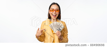 Microcredit and money concept. Stylish asian young woman in sunglasses, laughing happy, holding dollars cash, standing over white background Microcredit and money concept. Stylish asian young woman in sunglasses, laughing happy, holding dollars cash, standing over white background 88490698