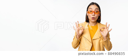 Enthusiastic asian girl in sunglasses, shows okay, ok sign in approval, smiling and laughing, approve, recommend smth, praise and compliment, standing over white background 88490835
