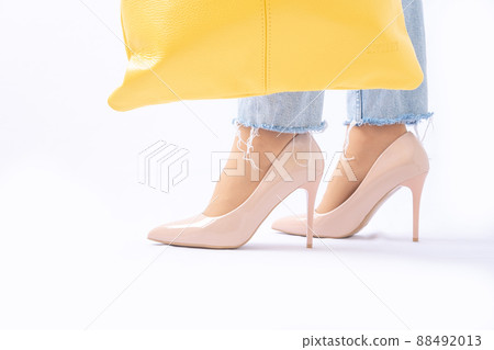 Slender female legs in patent leather shoes with high heels. Light blue ripped jeans. Yellow leather bag. Trendy pastel shades. Fashion Style Slender female legs in patent leather shoes with high heels. Light blue ripped jeans. Yellow leather bag. Trendy pastel shades. Fashion Style 88492013