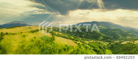 Aerial view of the endless lush pastures of the Carpathian expanses and agricultural land. Cultivated agricultural field. Rural mountain landscape at sunset. Ukraine. 88492203