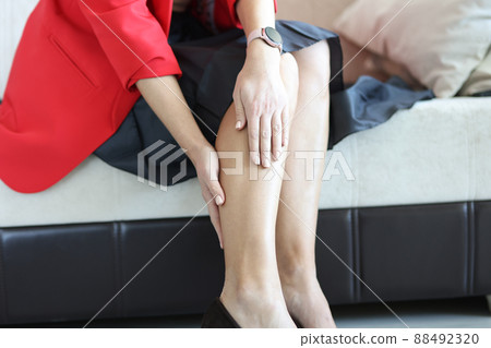 Young woman suffering from leg pain at home closeup 88492320