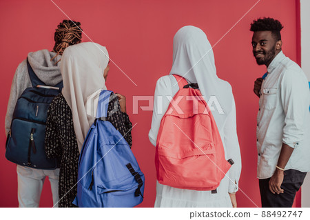 A group of African Muslim students with backpacks posing on a pink background. the concept of school education. 88492747