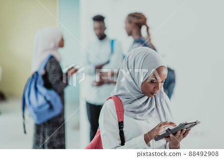 African female student with group of friends in background wearing traditional Islamic hijab clothes. Selectve focus  88492908